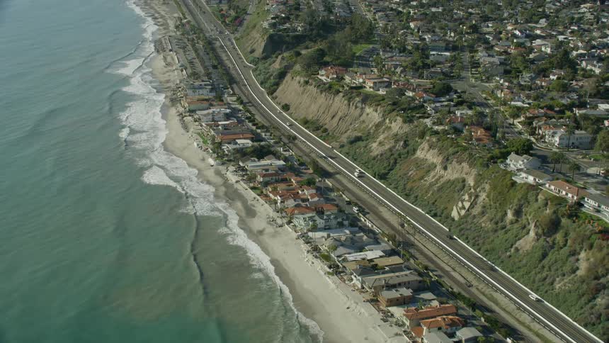 Slow motion aerial view of cars driving along the Pacific Coast Highway in Southern California