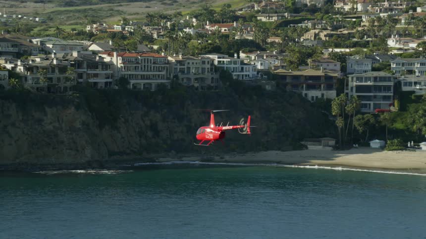 A helicopter flying near a coast with tall ocean cliffs in the background