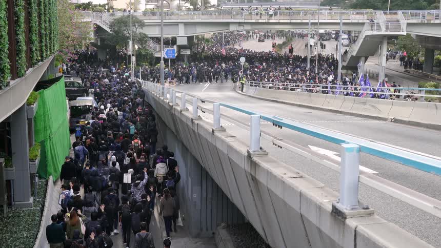 Crowd of people walk near a bridge in the city