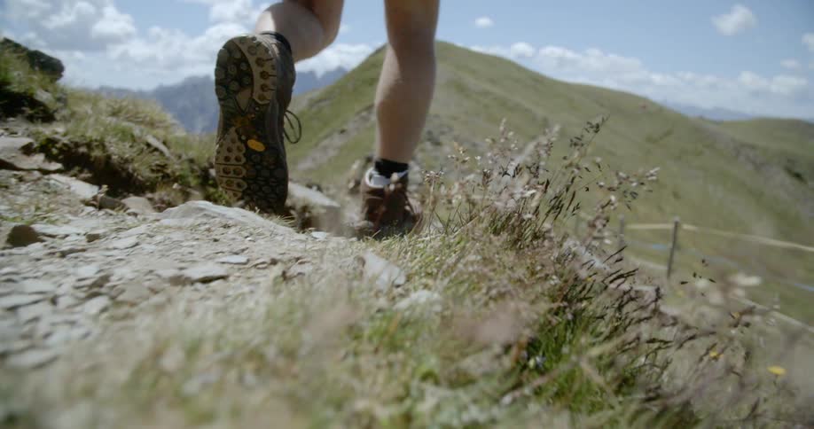 Close up of hiking boots walking on mountain ridge on a dirt trail