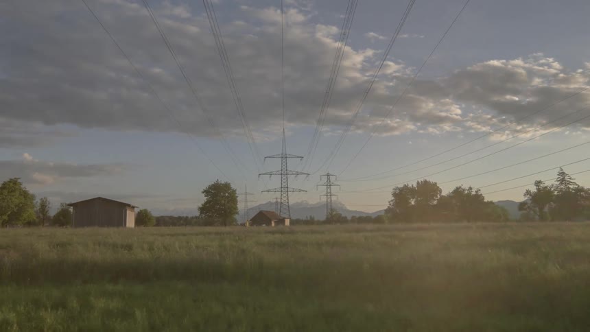 A grassy field with power lines and the sky in the background