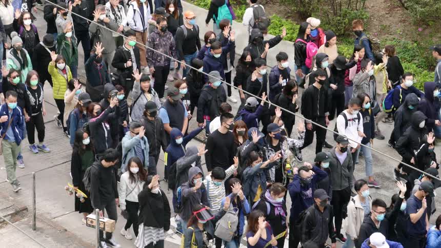 The crowd of protesters march on the sidewalk