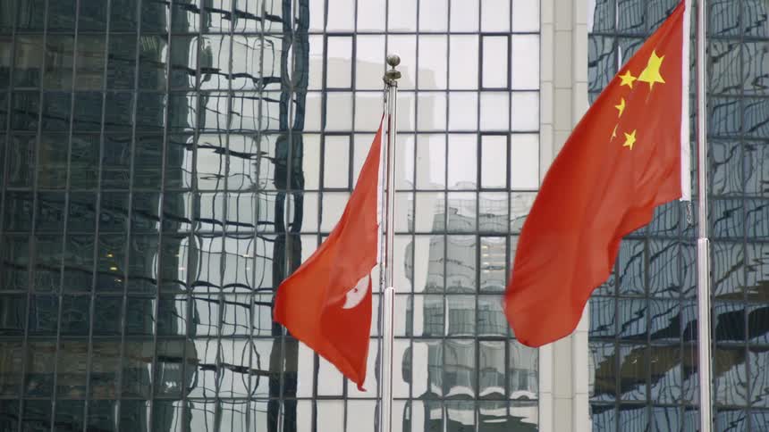 Two flags flying in the sky near a building
