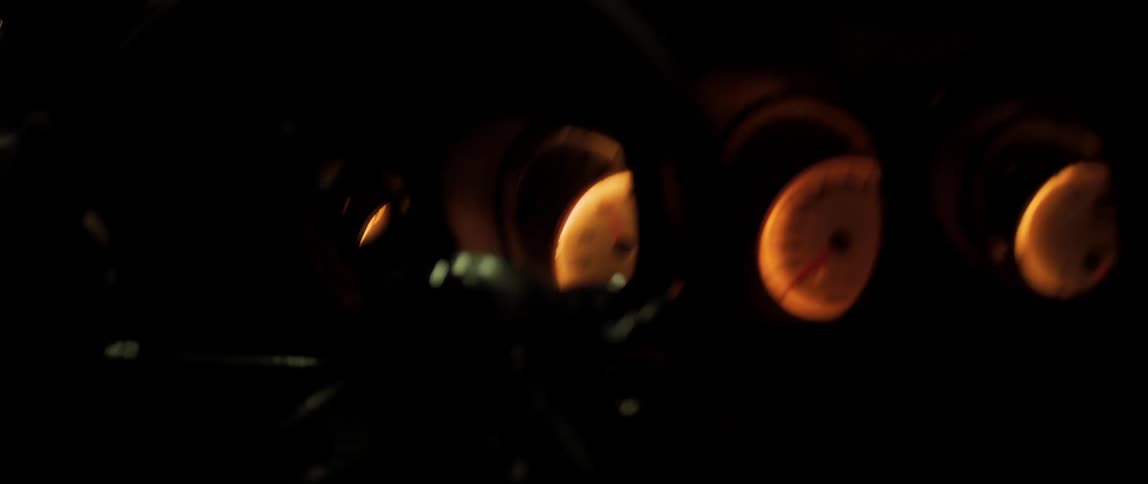 A car dashboard glows in a dark moving vehicle