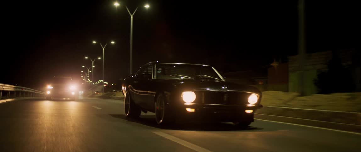Two cars drive down a road at night