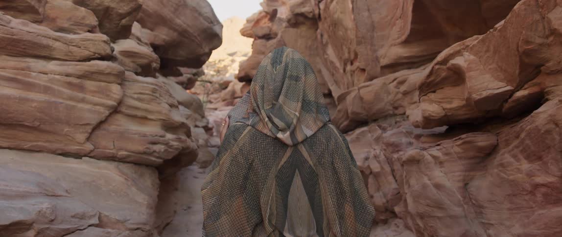 A woman is walking through a canyon outdoors