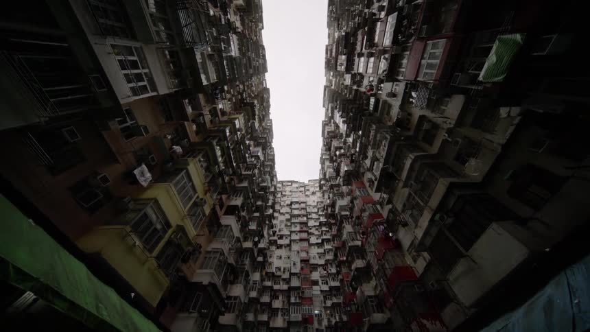 Tall buildings with balconies sit under a cloudy sky