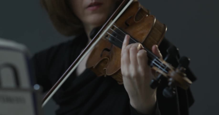 A woman is playing a violin in front of sheet music