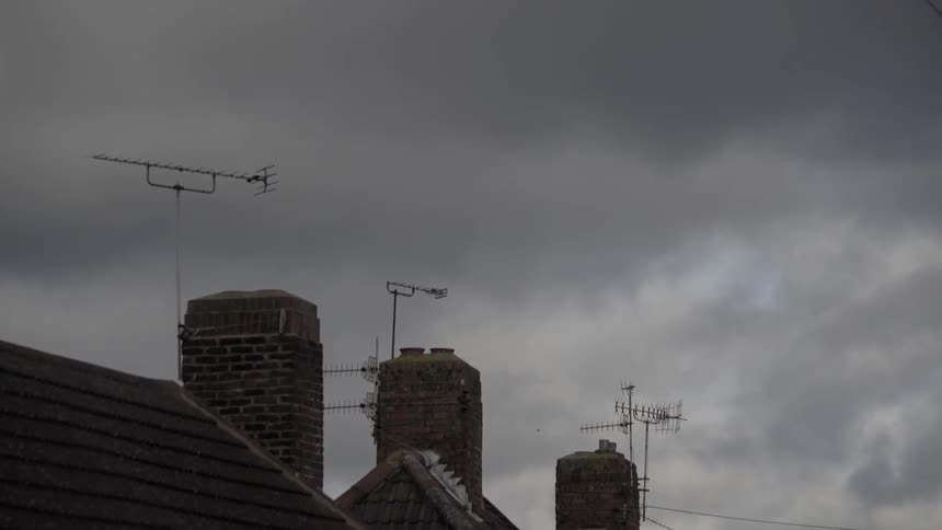 Dark clouds float over rooftops and chimneys