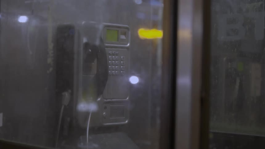 A bus drives by a payphone at night