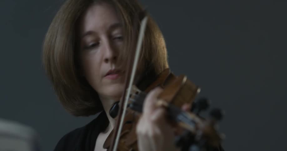 A woman plays a violin with passion