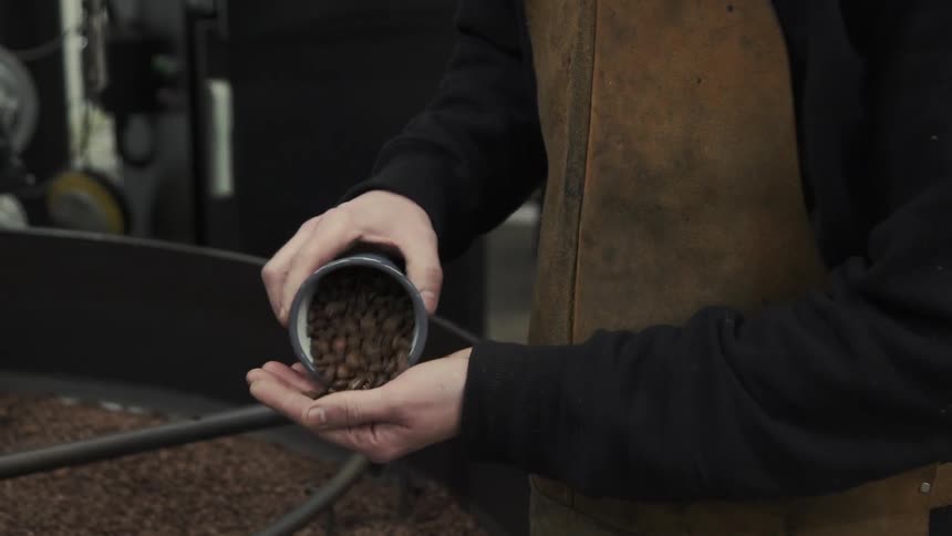 A person empties a cup with beans into his hand