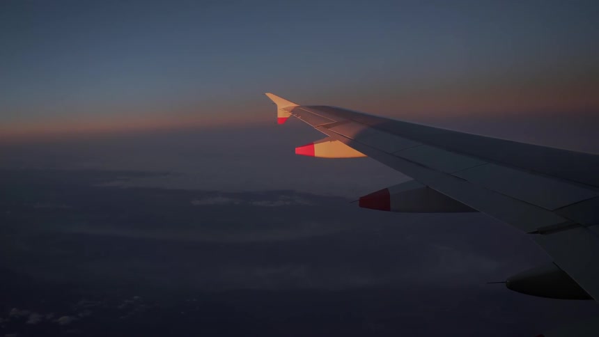 The wing of a plane in flight in the evening
