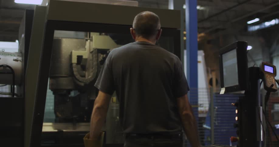 A man monitors and controls a factory machine
