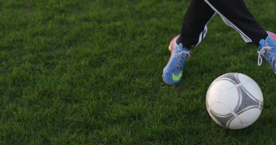 A person is kicking a soccer ball down a field