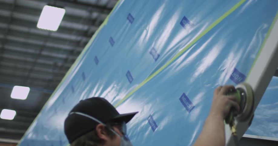 A man is using a sander on a wooden frame