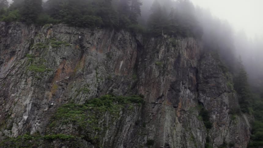 Clouds hover over a rocky cliff