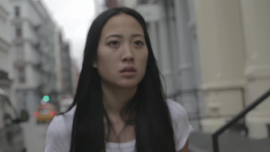 A woman is walking down a sidewalk in a city