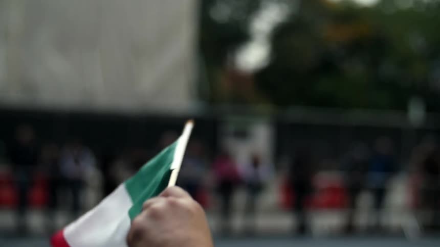 A person is waving a flag with people standing up ahead