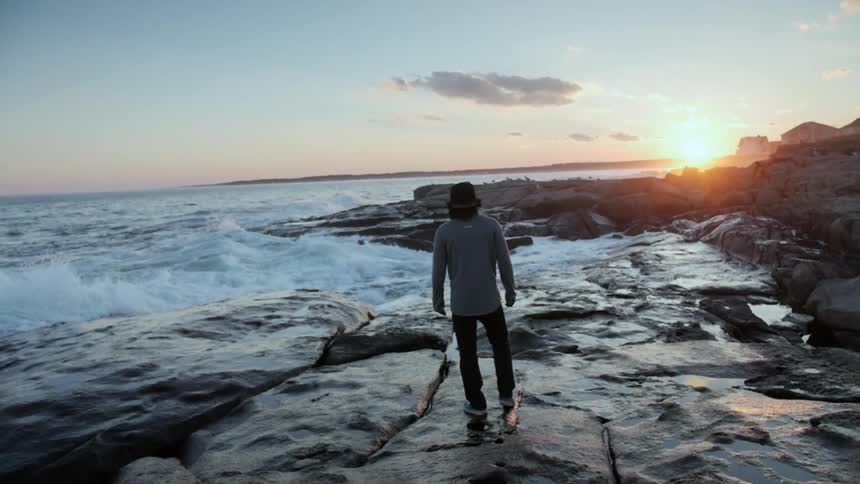 A man standing on rock next to the ocean