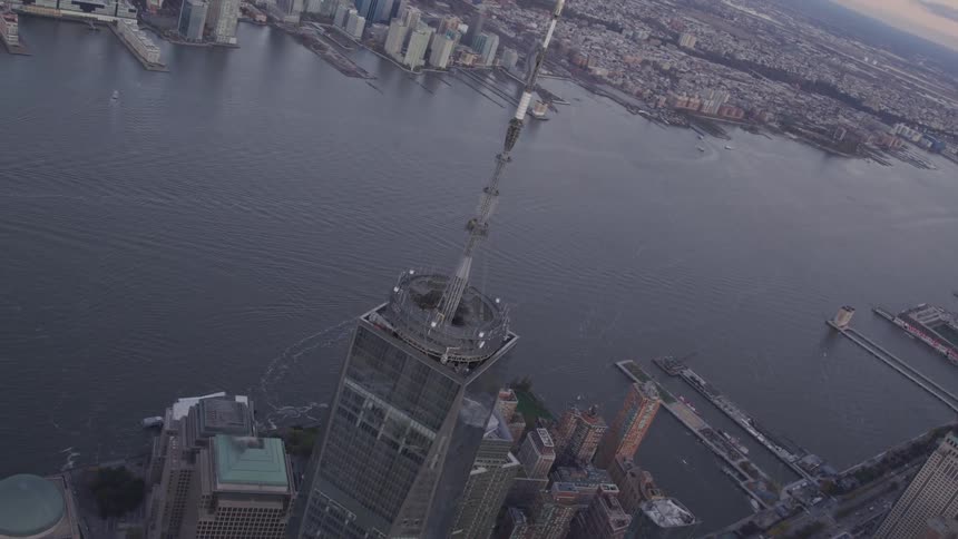 A large antenna on top of a skyscraper next to a river