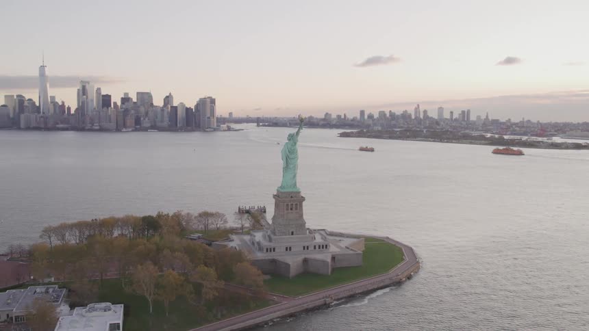 Aerial view of the statue of liberty and the surrounding water at dawn