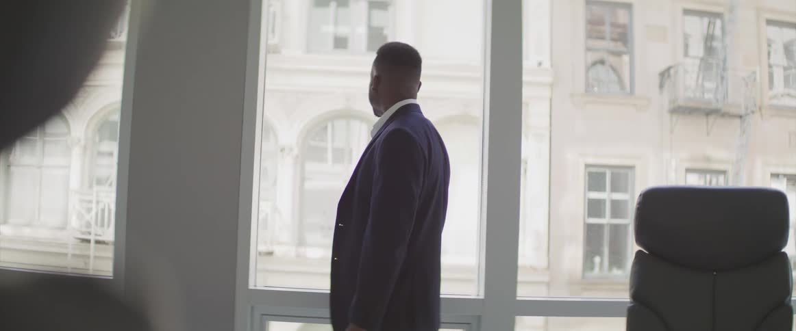 Black businessman looks out the window in the office