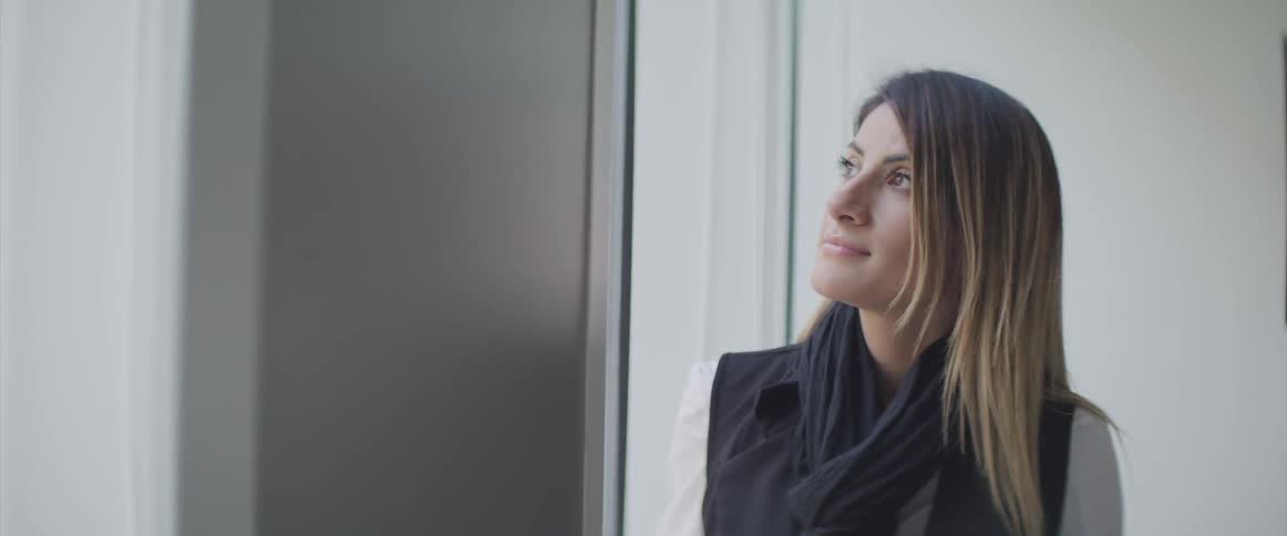A white woman with long hair looks out a window