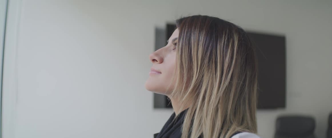 Blonde woman tilts her head back as she blinks her eyes