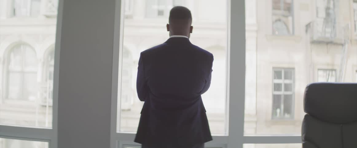 Black businessman looks out the window in the office