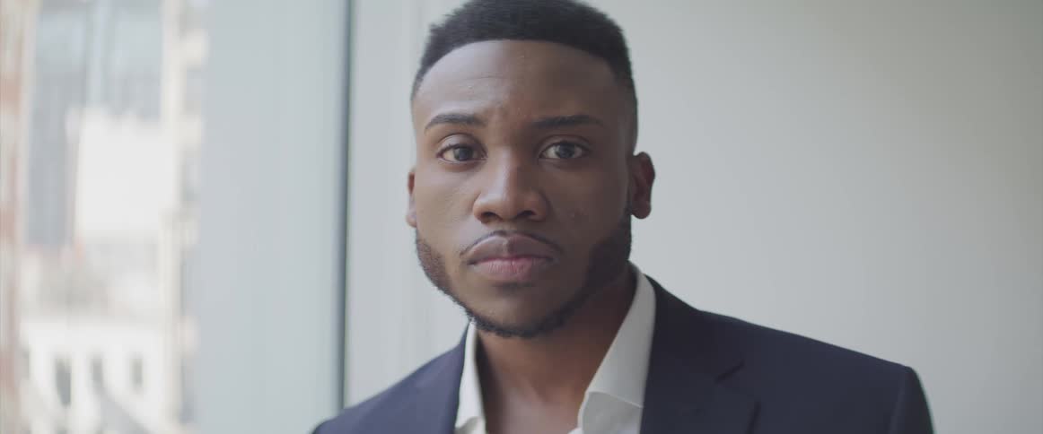 Black businessman looks sideways and turns his head to the camera in the office