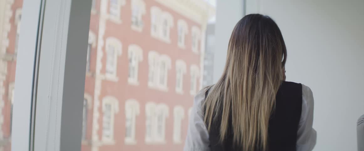 A woman walking near a window in a building