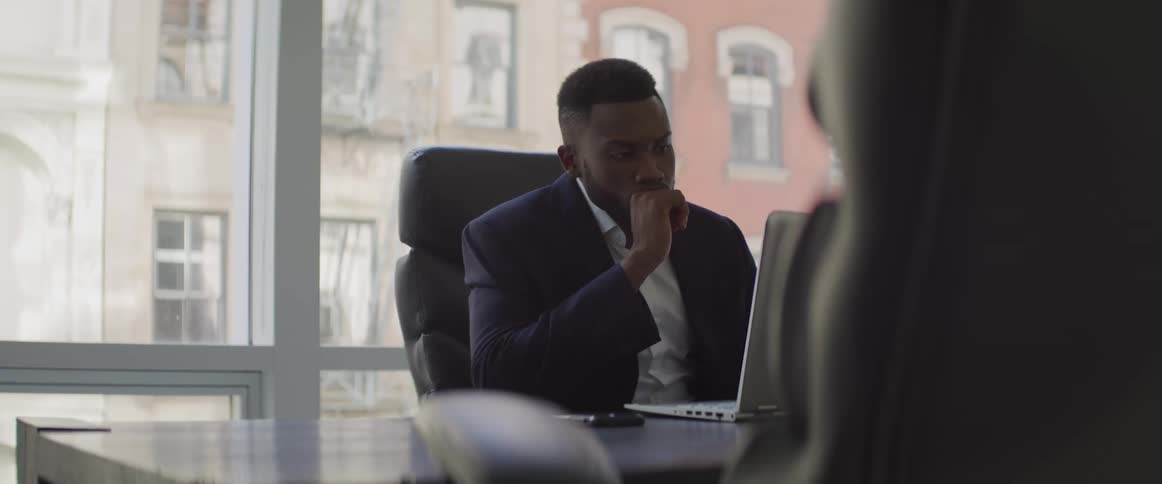 Businessman sitting at the table uses a laptop in the office