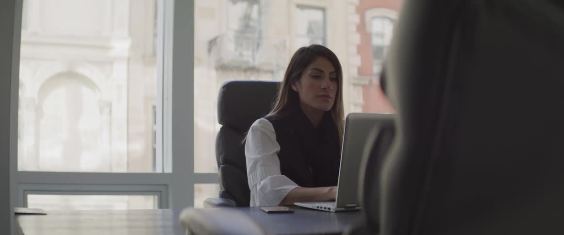 A woman sitting at a desk in an office using a laptop