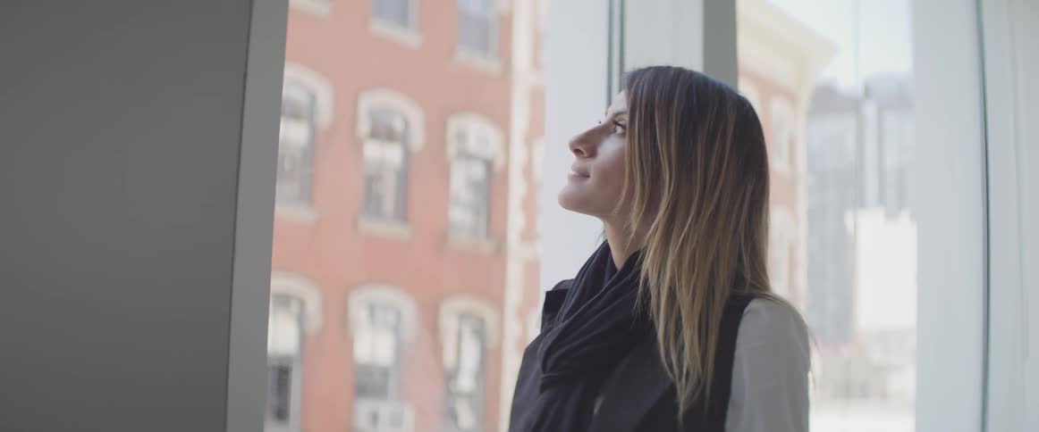 Woman standing next to window and looking out