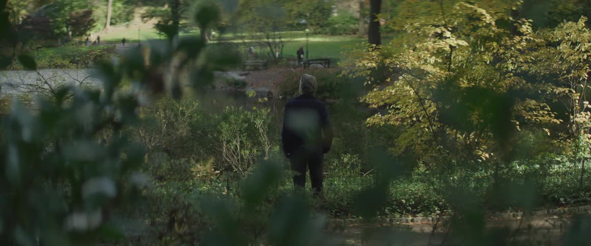 Businessman stands and watches the pond in the public park