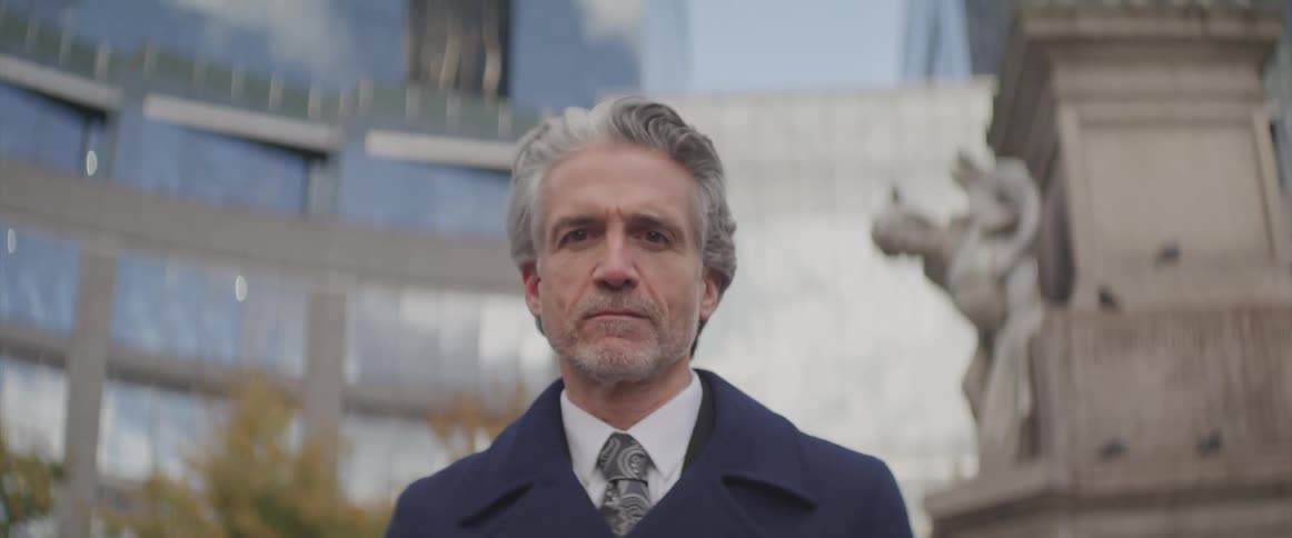 Businessman stands and stares at the camera next to the statue