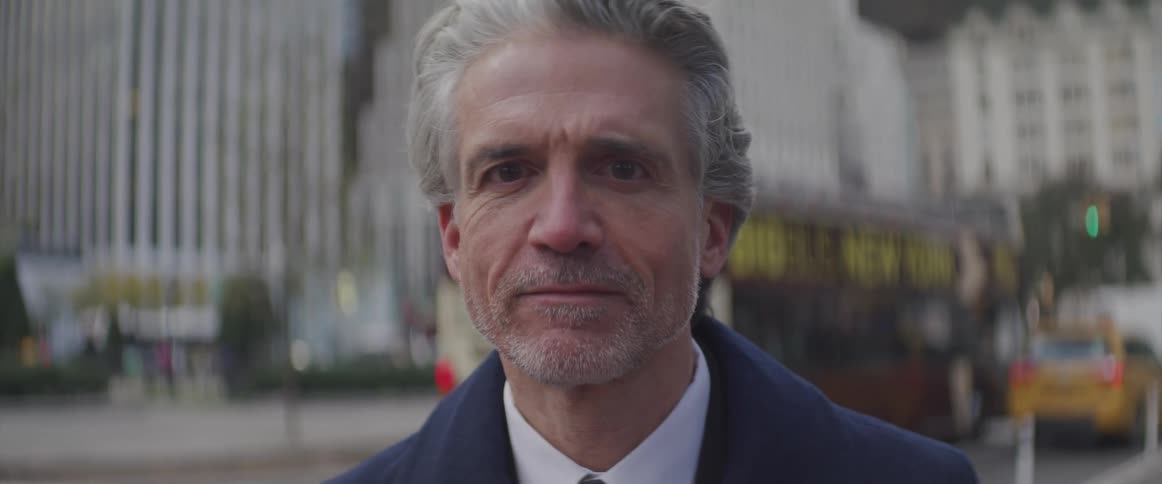 Businessman turns his head and looks at the camera in the city