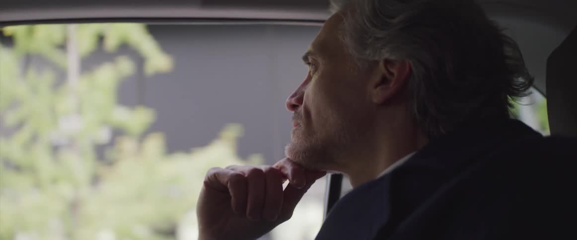 Side view of a businessman looking out the window of a moving car in the city