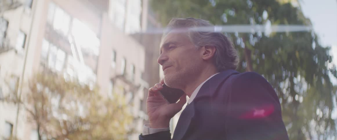 Businessman speaks on the smartphone in the street