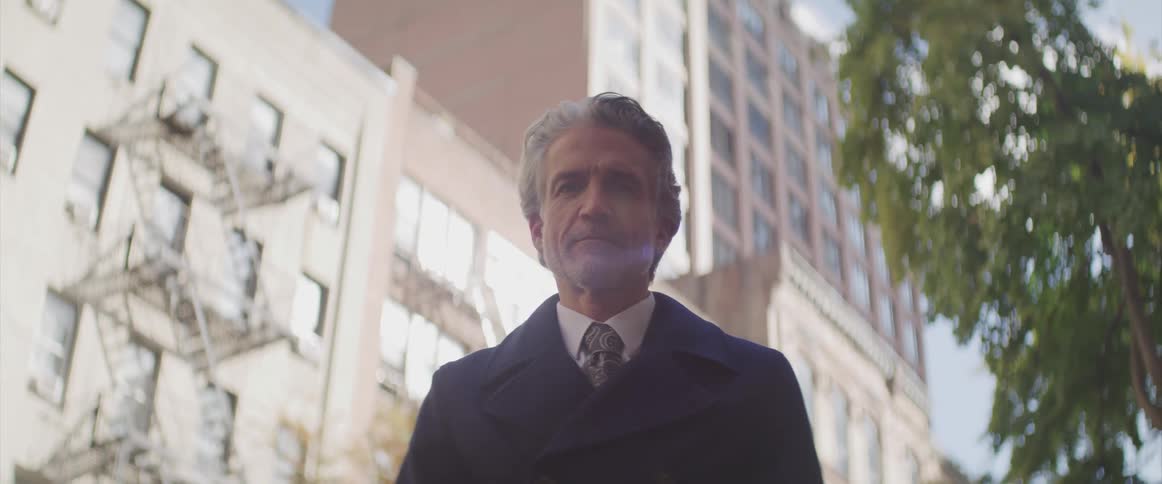 Businessman stands and stares at the camera in the street
