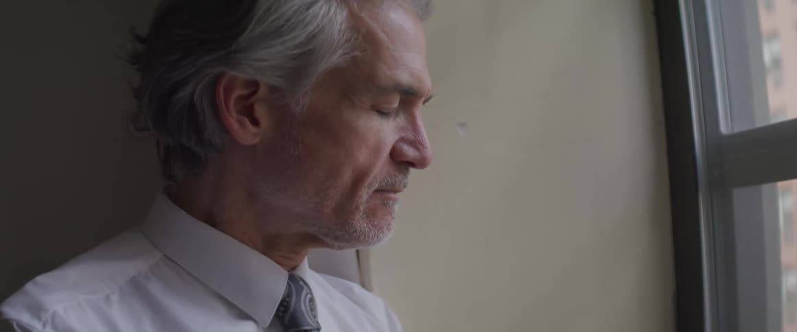 A man sits sadly at the window
