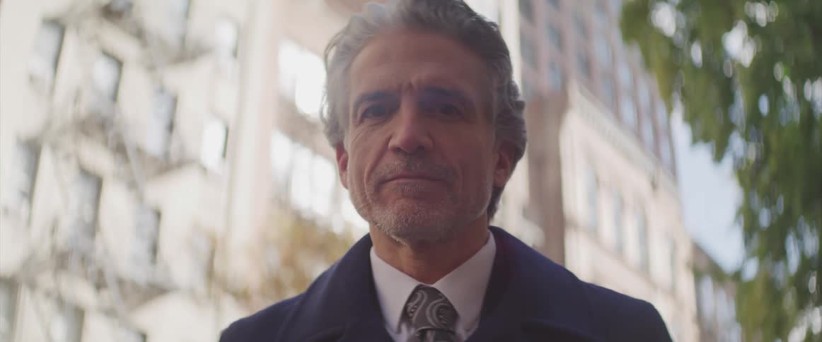 Businessman stands and looks down at the camera in the street