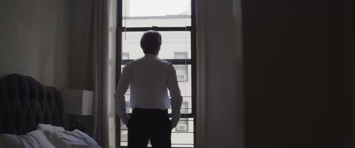 A man stands and looks out a window