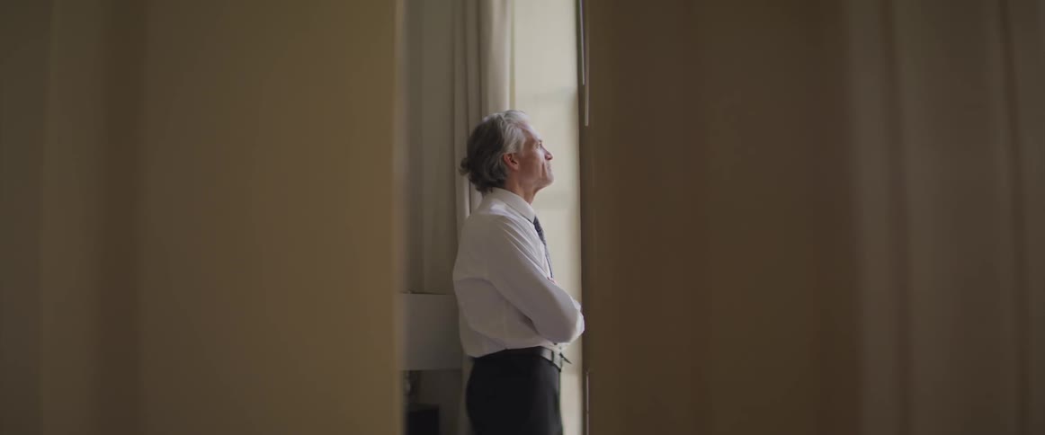 Businessman stands and looks out the window