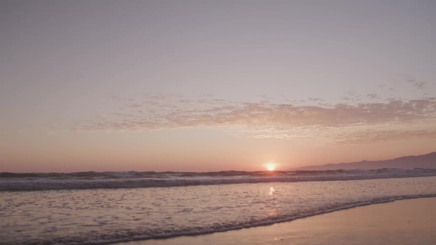 The sun goes down over the wavy ocean in the sky