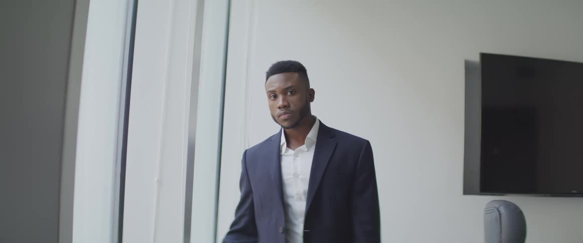 Black businessman stands in the office and stares at the camera