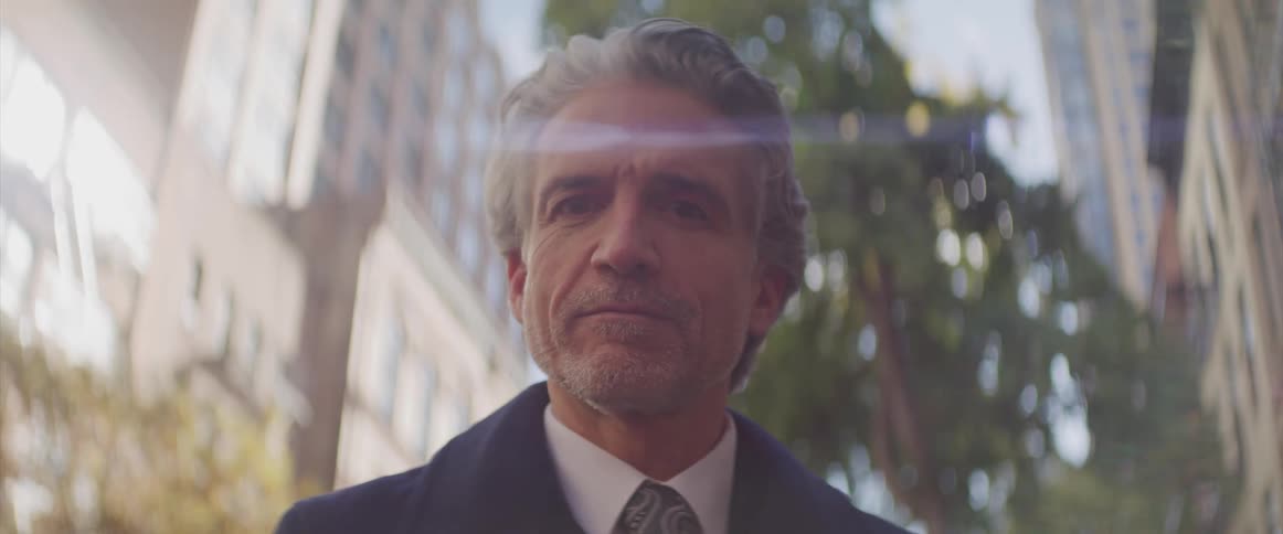 Senior businessman stands and looks at the camera in the centre of the city