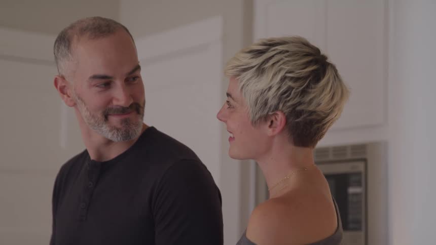 Couple looks and smile at each other in the kitchen