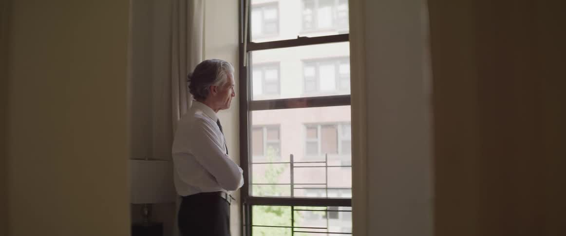 Businessman looks out the window in the apartment